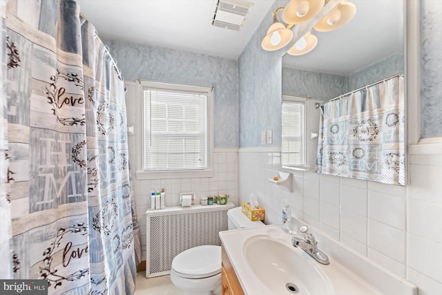 bathroom with toilet, vanity, tile walls, and a healthy amount of sunlight