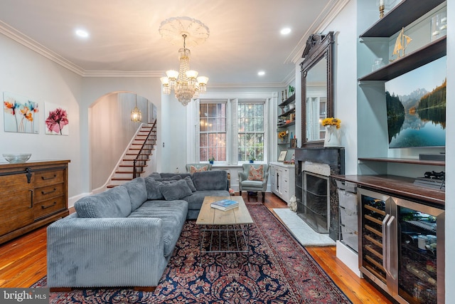 living room featuring bar area, wine cooler, wood-type flooring, and ornamental molding