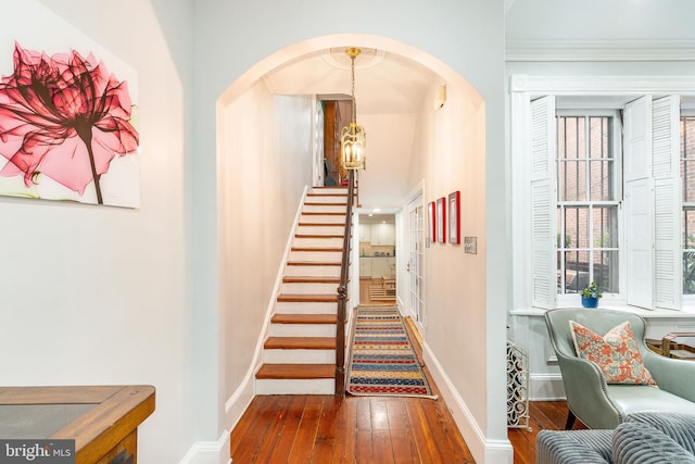 staircase featuring hardwood / wood-style floors, a notable chandelier, and crown molding