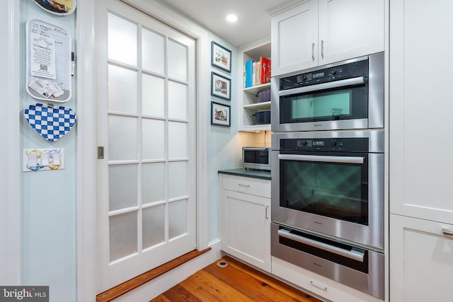 kitchen with white cabinetry, appliances with stainless steel finishes, and light hardwood / wood-style flooring