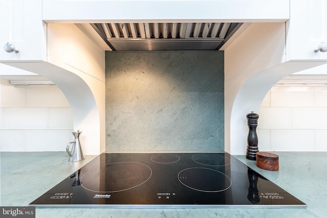 kitchen featuring range hood, black electric cooktop, and white cabinets