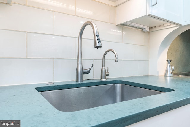 details featuring white cabinetry, sink, and backsplash