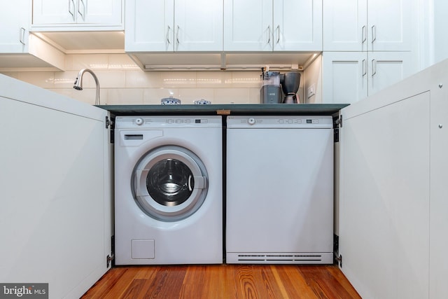 clothes washing area with separate washer and dryer and hardwood / wood-style flooring