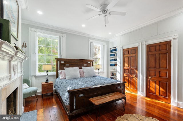 bedroom with dark hardwood / wood-style flooring, ornamental molding, a high end fireplace, and ceiling fan