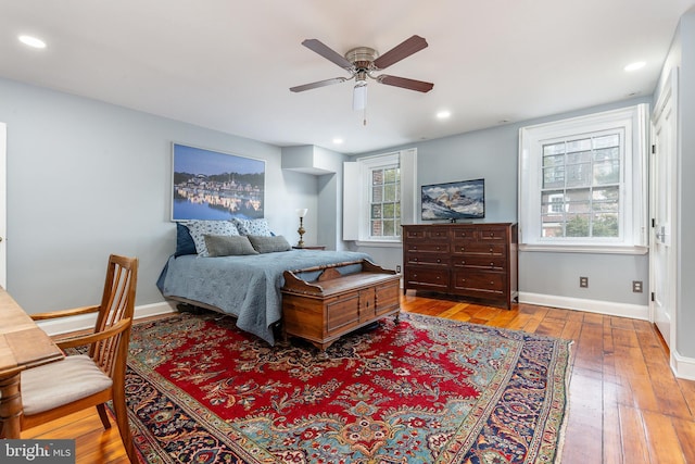 bedroom with multiple windows, wood-type flooring, and ceiling fan