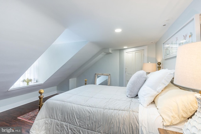 bedroom featuring dark hardwood / wood-style flooring, lofted ceiling, and a closet