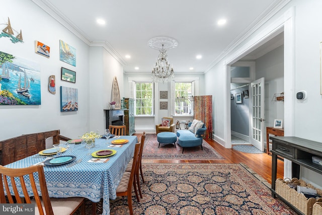 dining room featuring an inviting chandelier, wood-type flooring, ornamental molding, and french doors