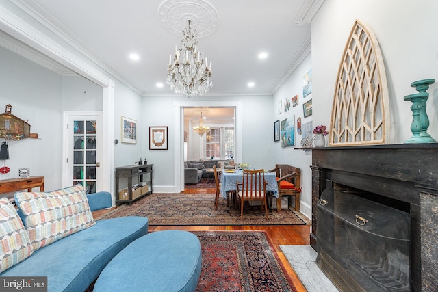 living room with a notable chandelier, hardwood / wood-style flooring, and crown molding