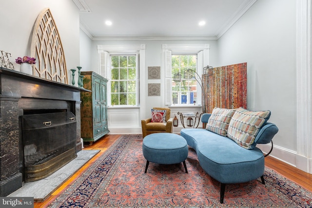 living area with wood-type flooring, a high end fireplace, and ornamental molding