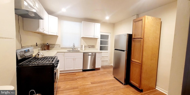 kitchen with sink, stainless steel appliances, white cabinets, light hardwood / wood-style flooring, and ventilation hood