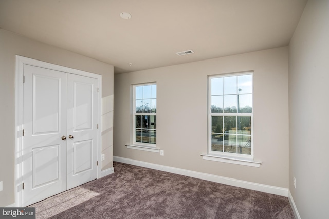 unfurnished bedroom featuring a closet and dark carpet