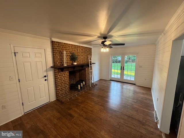 unfurnished living room with french doors, crown molding, a fireplace, dark wood-type flooring, and ceiling fan