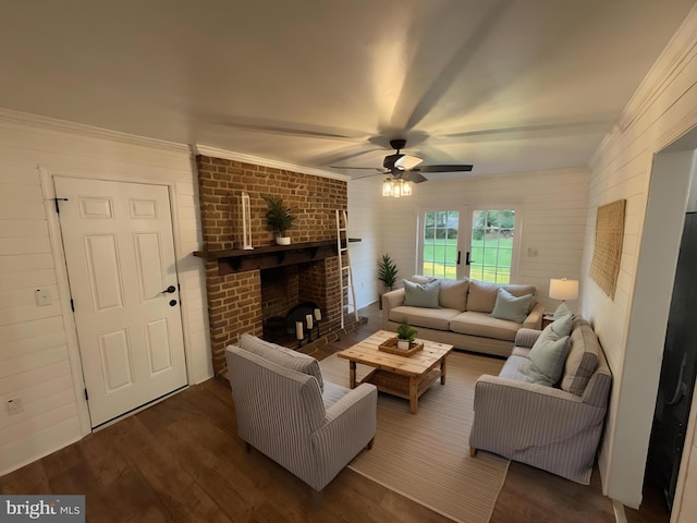 living area with wood finished floors, a ceiling fan, a fireplace, wood walls, and ornamental molding