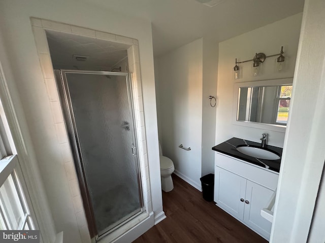 full bathroom with toilet, wood finished floors, vanity, a stall shower, and baseboards