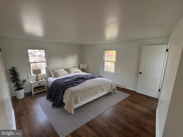 bedroom featuring multiple windows and dark hardwood / wood-style floors