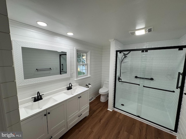 bathroom with toilet, a shower with door, hardwood / wood-style flooring, ornamental molding, and vanity