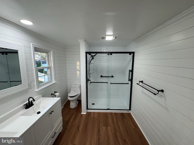 bathroom with toilet, hardwood / wood-style floors, ornamental molding, vanity, and walk in shower