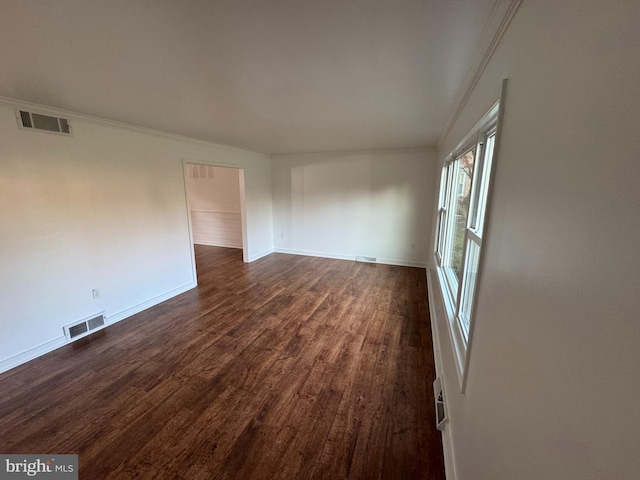 empty room featuring baseboards, ornamental molding, visible vents, and dark wood-type flooring