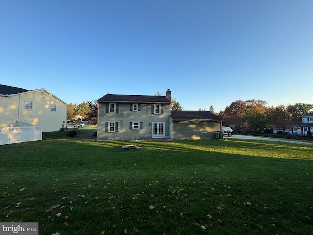 rear view of property featuring french doors, a chimney, and a lawn