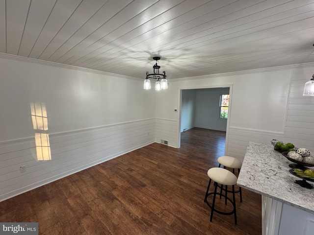 dining area featuring crown molding, dark wood finished floors, wood walls, and a wainscoted wall