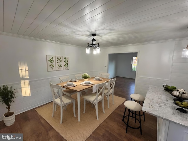 dining room with crown molding, dark wood-type flooring, a wainscoted wall, and an inviting chandelier