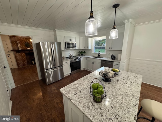 kitchen featuring white cabinets, dark hardwood / wood-style floors, light stone countertops, pendant lighting, and appliances with stainless steel finishes