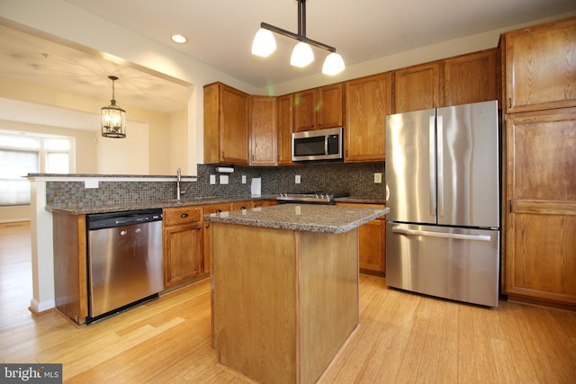 kitchen featuring pendant lighting, a center island, decorative backsplash, dark stone countertops, and stainless steel appliances