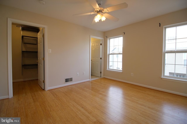 unfurnished bedroom with light hardwood / wood-style floors, a spacious closet, and a closet