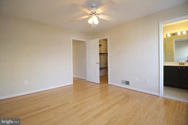 unfurnished bedroom with ceiling fan, light wood-type flooring, sink, and connected bathroom