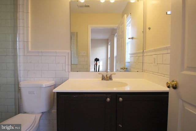 bathroom with vanity, toilet, and tile walls