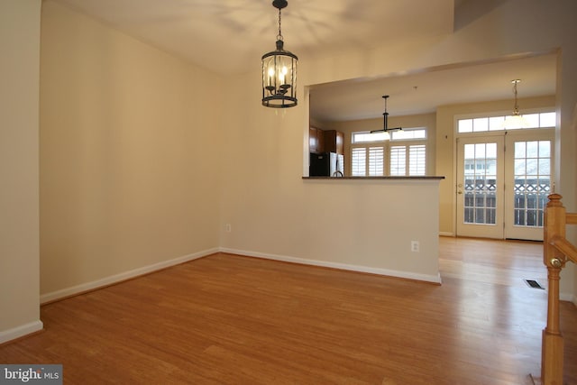 spare room featuring light hardwood / wood-style flooring and a chandelier