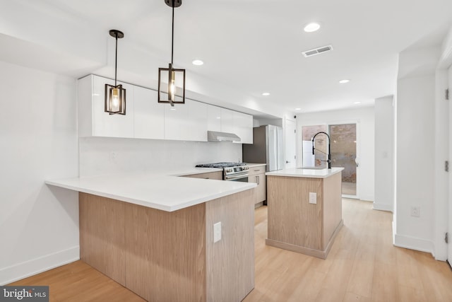 kitchen featuring kitchen peninsula, white cabinetry, light wood-type flooring, sink, and decorative light fixtures