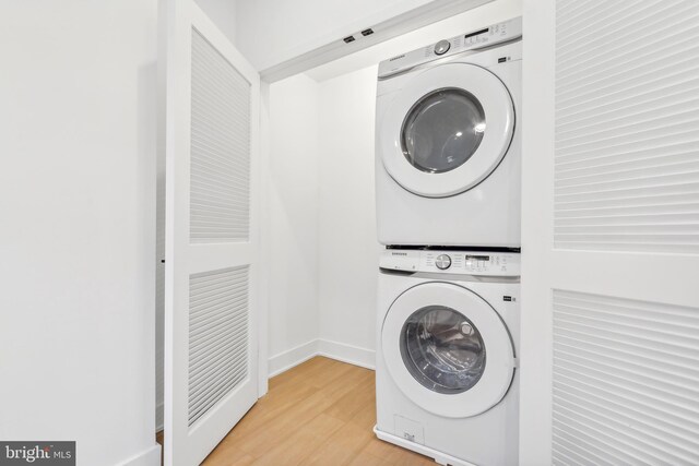 washroom with hardwood / wood-style floors and stacked washer and dryer