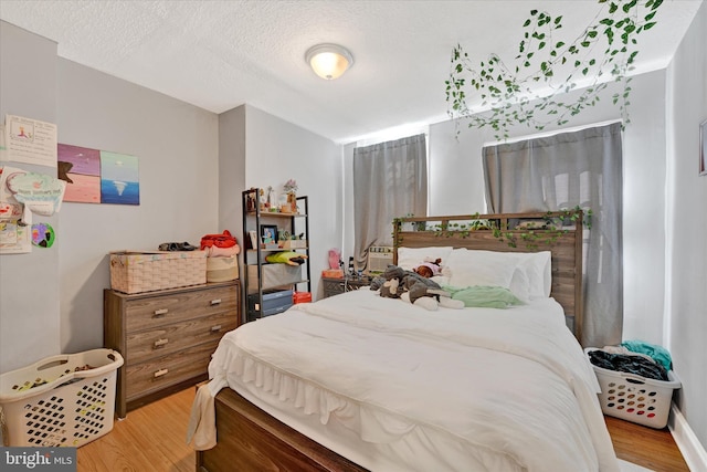 bedroom with light hardwood / wood-style flooring and a textured ceiling