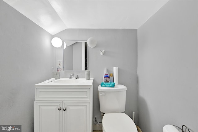 bathroom with vanity, toilet, and lofted ceiling