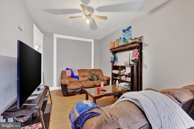 living room with light hardwood / wood-style flooring, a textured ceiling, and ceiling fan