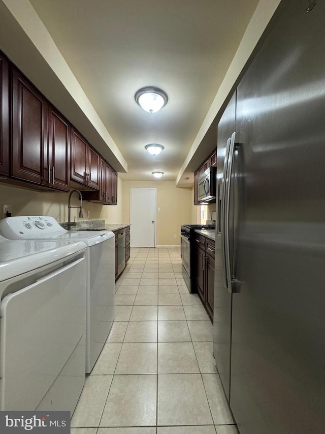 clothes washing area featuring sink, light tile patterned floors, and washer and clothes dryer