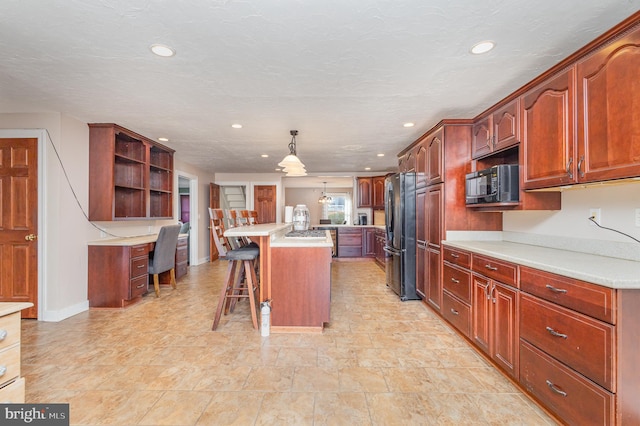 kitchen featuring stainless steel fridge, a textured ceiling, a kitchen bar, pendant lighting, and a kitchen island with sink