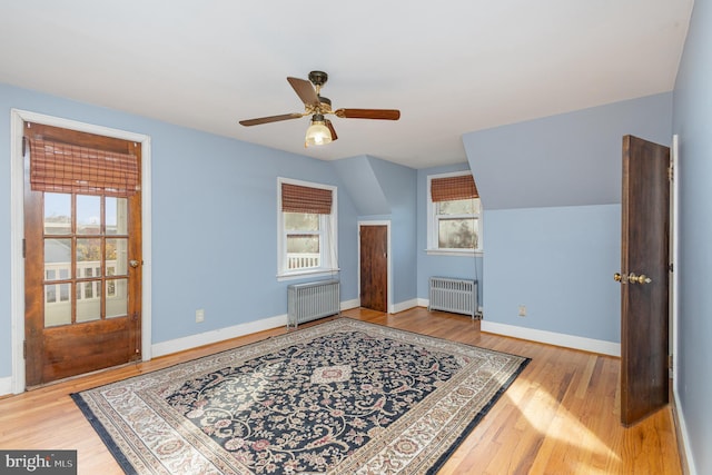 additional living space with radiator heating unit, wood-type flooring, lofted ceiling, and ceiling fan