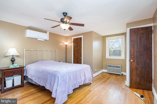 bedroom featuring a wall unit AC, radiator, ceiling fan, and light hardwood / wood-style flooring