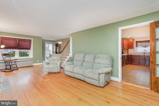 living room featuring light hardwood / wood-style floors, sink, and radiator