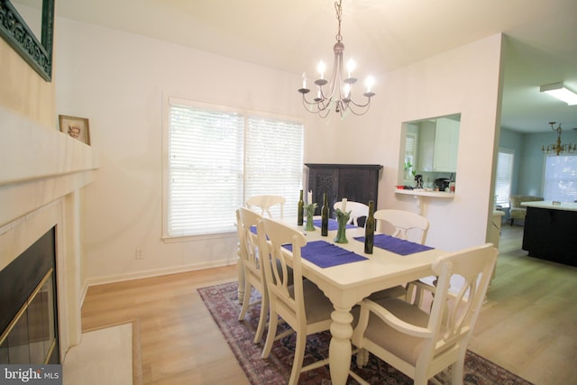 dining area featuring a premium fireplace, a notable chandelier, and light wood-type flooring