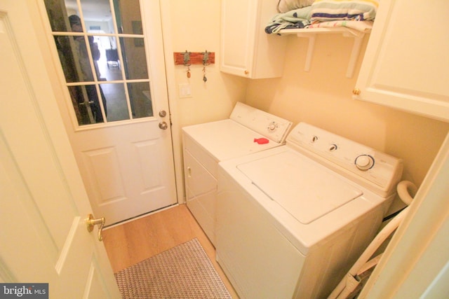 laundry area featuring washer and clothes dryer, hardwood / wood-style flooring, and cabinets