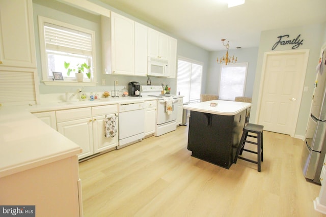 kitchen with a center island, light hardwood / wood-style flooring, decorative light fixtures, and white appliances