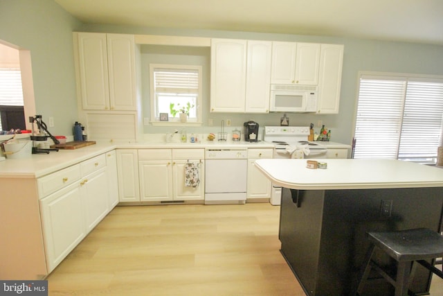 kitchen featuring white cabinets, kitchen peninsula, light wood-type flooring, and white appliances