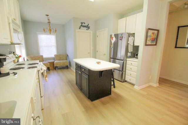 kitchen featuring a breakfast bar area, a kitchen island, white cabinetry, decorative light fixtures, and white appliances