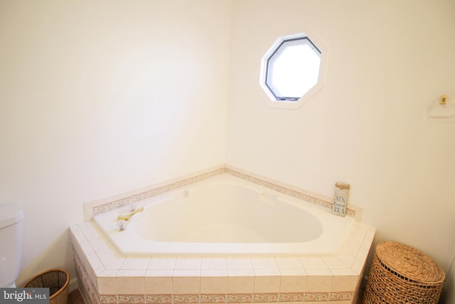 bathroom featuring a relaxing tiled tub and toilet