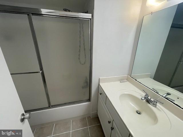 bathroom with enclosed tub / shower combo, vanity, and tile patterned floors