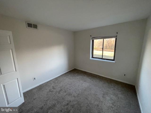 unfurnished room featuring dark colored carpet