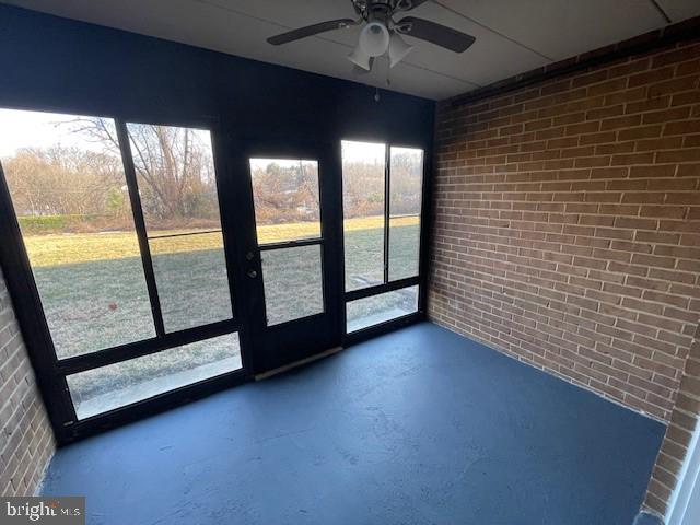 unfurnished sunroom with ceiling fan